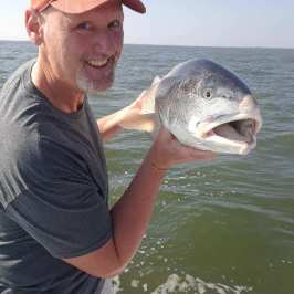 a man holding a fish in the water