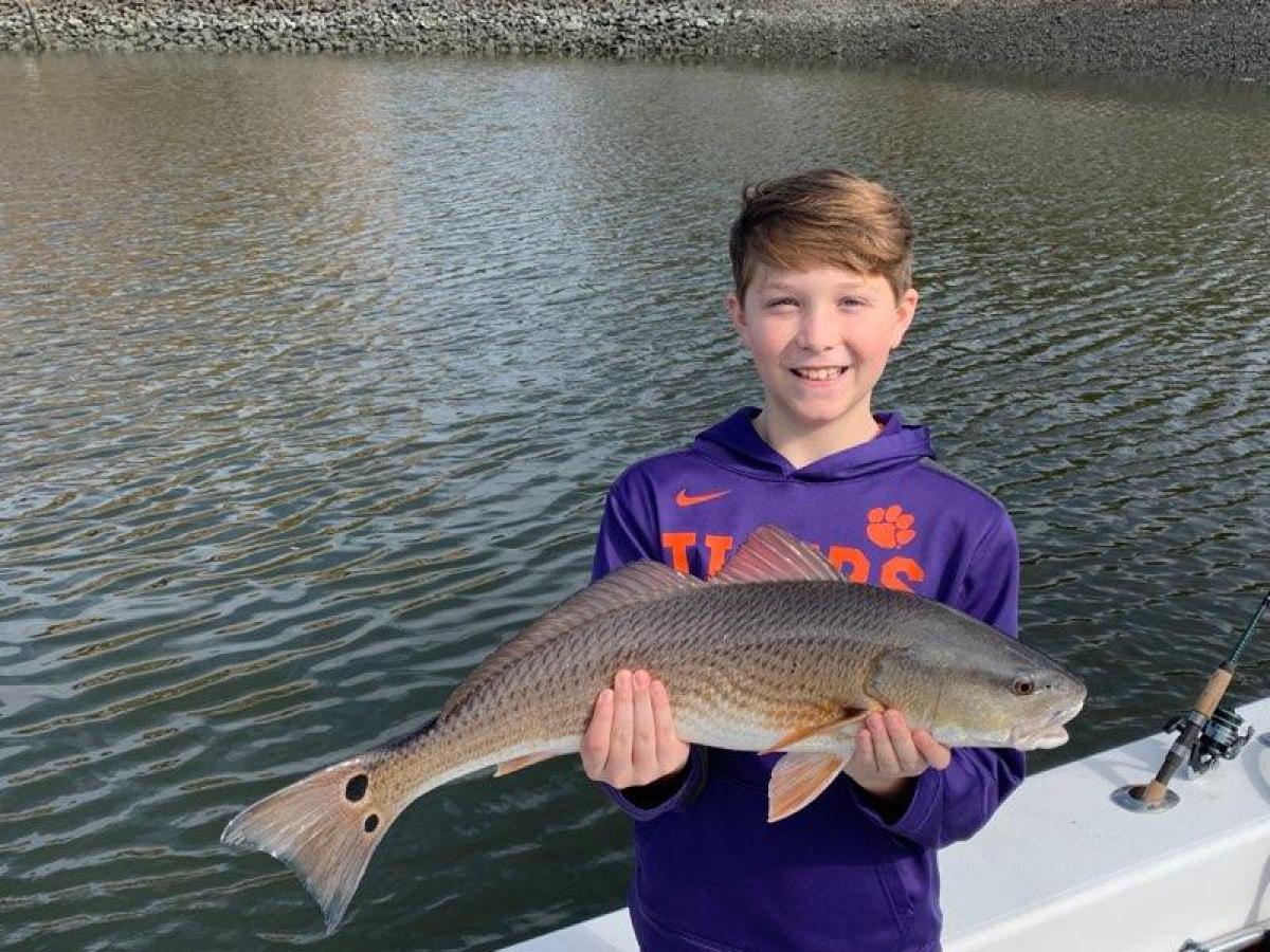 a young boy holding a fish in the water