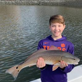 a young boy holding a fish in the water