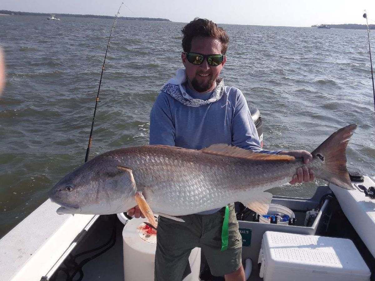 a man holding a fish on a boat in a body of water