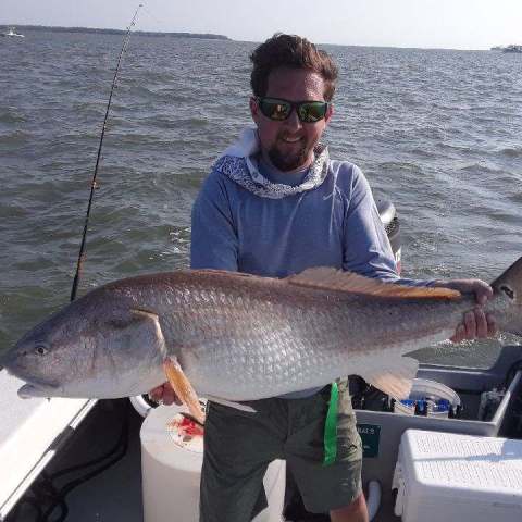a man holding a fish on a boat in a body of water