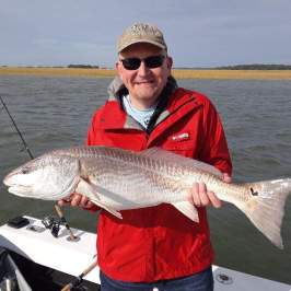 a man holding a fish on a boat in a body of water