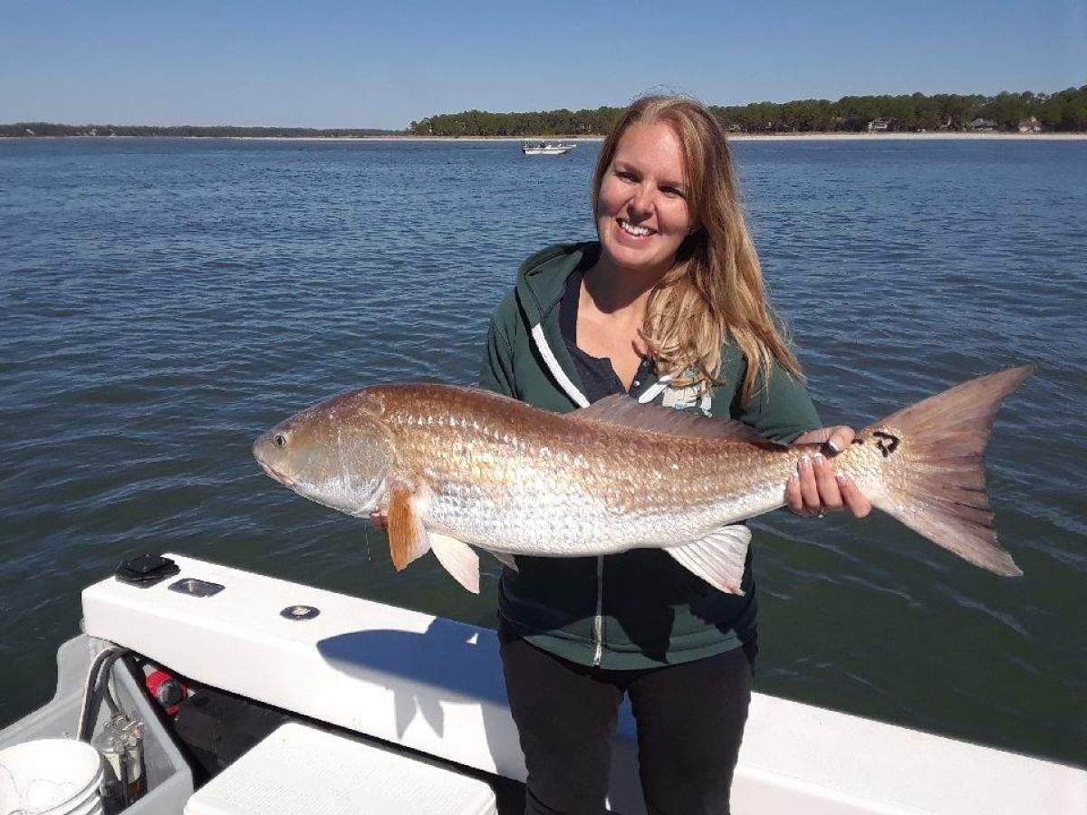 a person holding a fish in front of a body of water