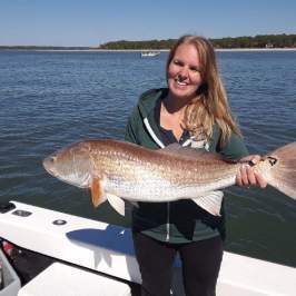 a person holding a fish in front of a body of water