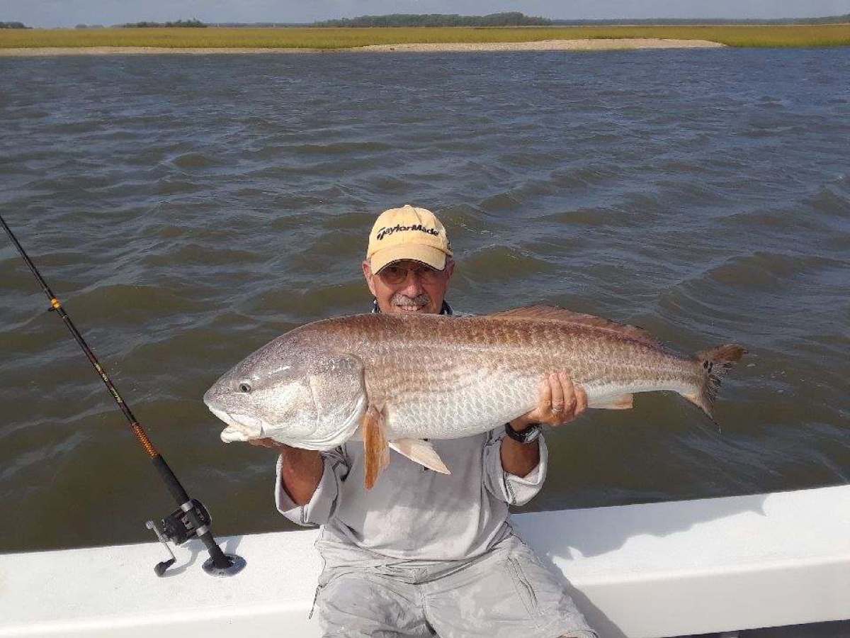 a person holding a fish on a boat in a body of water